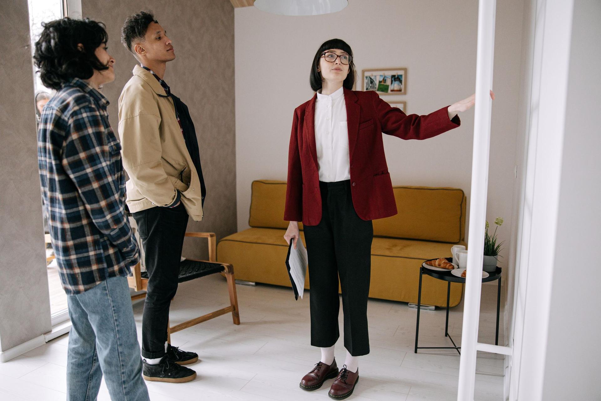 An agent shows two buyers around a furnished apartment