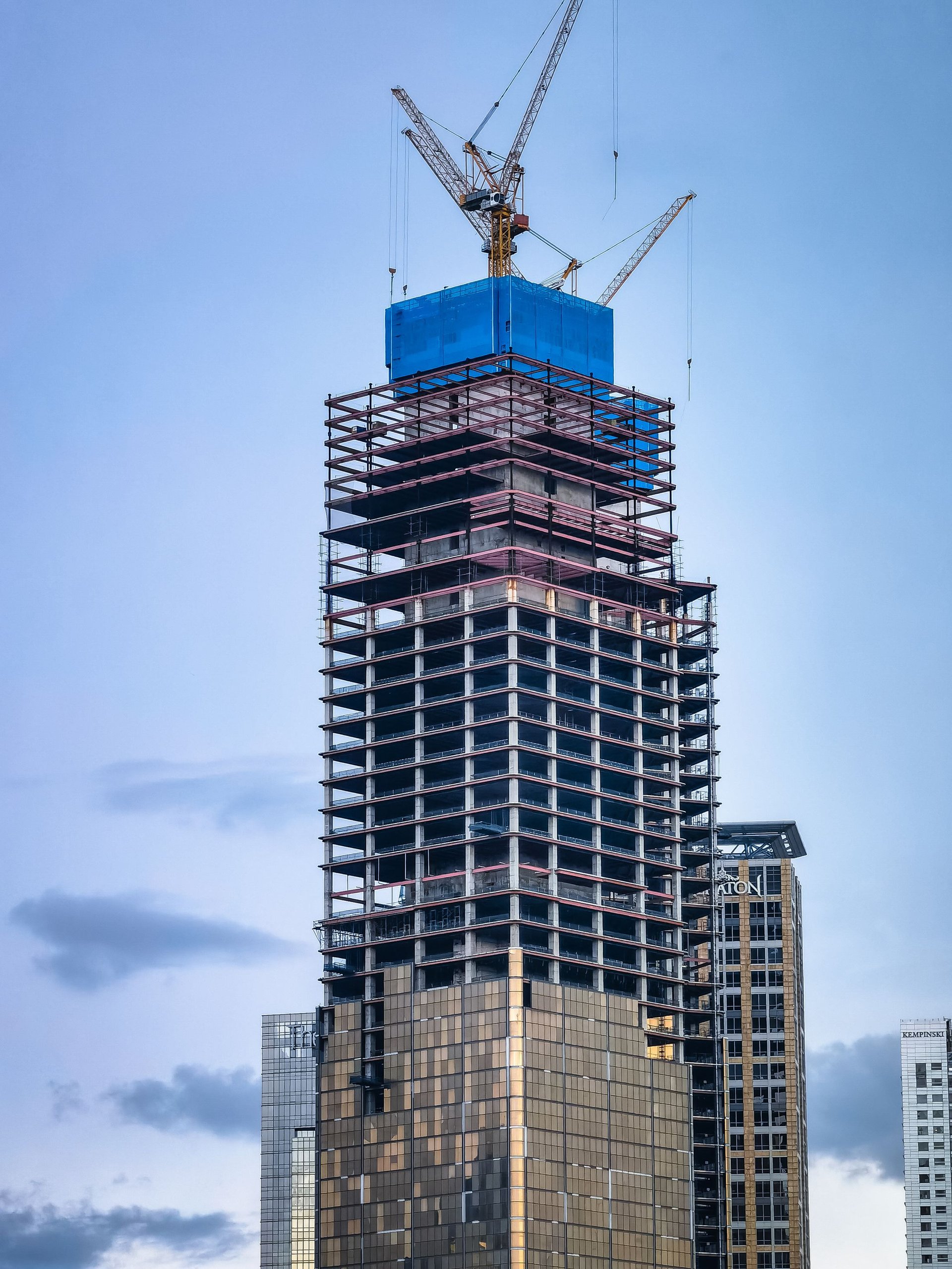 Glass tower under construction topped by a crane