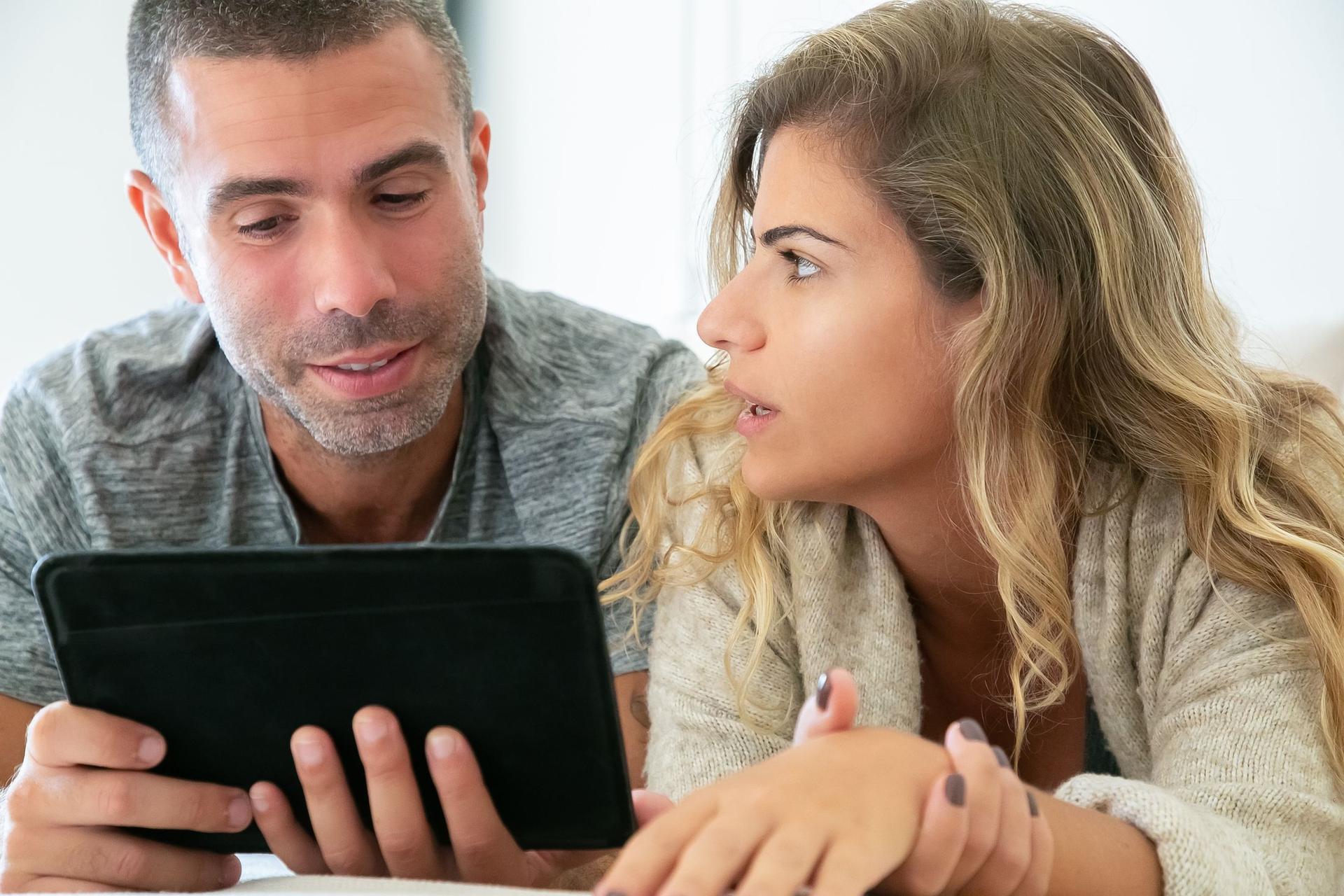 A couple reads an investment guide together on a tablet